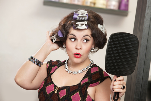 Proud woman in curlers looking in a mirror